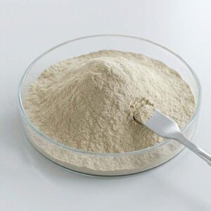 A glass petri dish filled with light beige powder of organic bentonite and organoclay rheological additive BT-184, with a metal spatula.