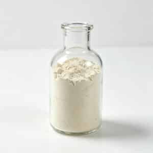A clear glass bottle filled with white powder of organic bentonite and organoclay rheological additive BT-875.